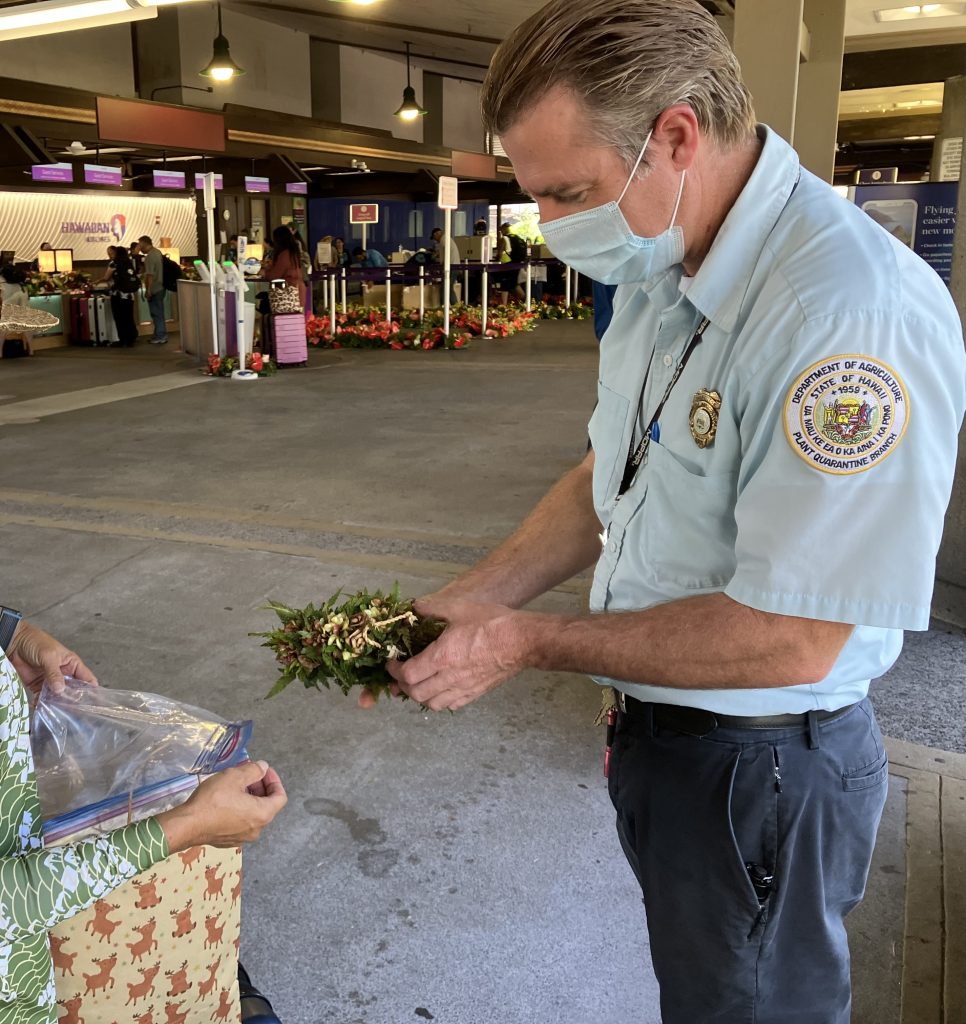 Ag inspector with ohia lei at airport